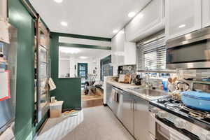 Kitchen with sink, stainless steel appliances, a barn door, and white cabinets