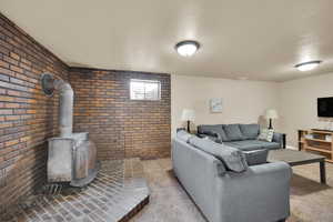 Living room featuring brick wall, light carpet, and a wood stove