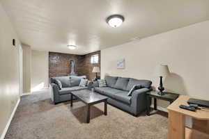 Living room with brick wall, light colored carpet, a textured ceiling, and a wood stove