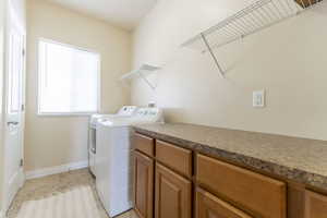 Laundry area with washing machine and dryer and light tile patterned flooring