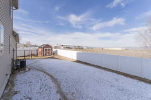 Snowy yard with cooling unit and a storage shed