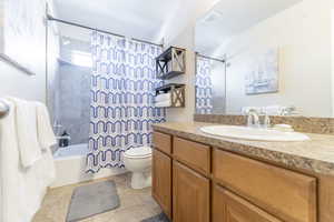 Full bathroom with tile patterned flooring, vanity, shower / bath combination with curtain, and toilet