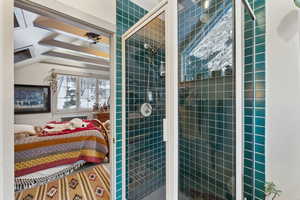 Bathroom featuring radiator heating unit, vaulted ceiling, and a tile shower