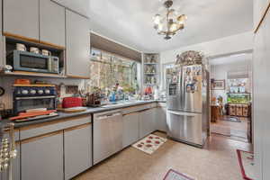 Kitchen with appliances with stainless steel finishes, a healthy amount of sunlight, sink, and a notable chandelier