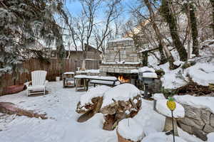 Snowy yard featuring an outdoor stone fireplace