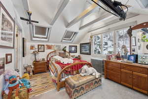 Carpeted bedroom with radiator and vaulted ceiling with beams