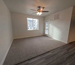 Living room with a textured ceiling, dark hardwood / wood-style floors, and ceiling fan