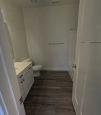 Shared Bathroom featuring hardwood / wood-style flooring, vanity, and toilet