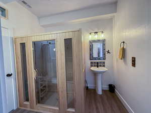 Bathroom with LVP floors, sink, shower with shower curtain and sauna