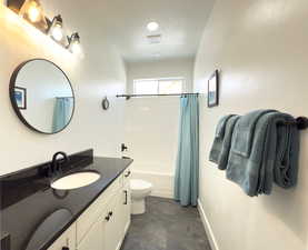 Full bathroom featuring vanity, shower / tub combo with curtain, and toilet