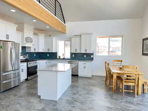 Kitchen with stainless steel appliances, beam ceiling, a center island, and white cabinets