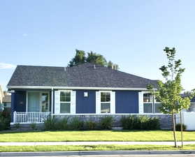 View of front of house featuring a porch, roof with shingles, a front yard, and stucco siding