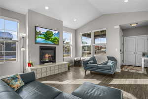 Living room with vaulted ceiling, / wood-style floors, and a fireplace