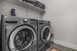 Clothes washing area featuring dark tile patterned floors and washing machine and clothes dryer