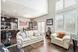 Living room with dark wood-type flooring, an inviting chandelier, and a textured ceiling