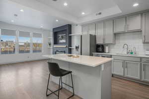 Kitchen with stainless steel refrigerator with ice dispenser, gray cabinets, sink, and a kitchen island