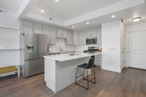 Kitchen featuring stainless steel appliances, a kitchen island, dark hardwood / wood-style floors, and a kitchen breakfast bar