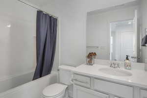 Full bathroom featuring shower / bath combination with curtain, vanity, and toilet