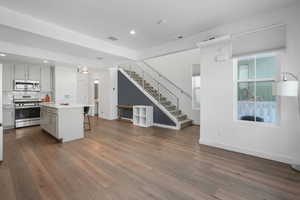 Kitchen with stainless steel appliances, wood-type flooring, a center island, and a breakfast bar area