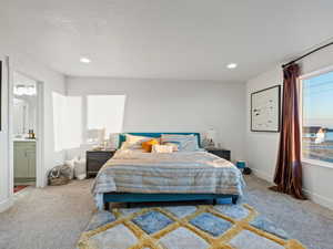 Bedroom featuring connected bathroom, light carpet, and a textured ceiling