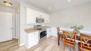 Kitchen featuring light hardwood / wood-style flooring, white cabinets, and appliances with stainless steel finishes