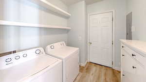 Laundry area featuring cabinets, washing machine and clothes dryer, and light wood-type flooring