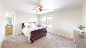 Bedroom featuring ensuite bath, light colored carpet, and ceiling fan