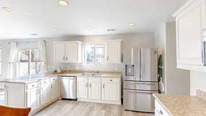 Kitchen featuring sink, light wood-type flooring, appliances with stainless steel finishes, kitchen peninsula, and white cabinets