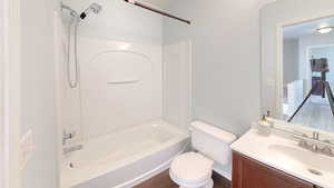 Full bathroom with washtub / shower combination, vanity, toilet, and hardwood / wood-style floors