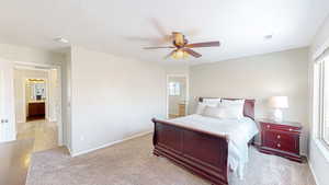 Carpeted bedroom featuring ceiling fan and ensuite bath