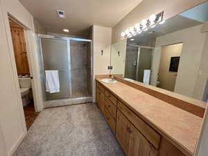 Bathroom with an enclosed shower, vanity, and toilet