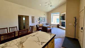 Dining area featuring light tile patterned floors, high vaulted ceiling, and ceiling fan