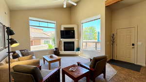 Tiled living room featuring ceiling fan, plenty of natural light, and vaulted ceiling