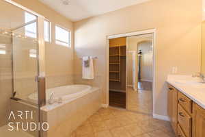 Master bathroom with tile patterned flooring, vanity, and separate shower and tub with door to large walk-in closet