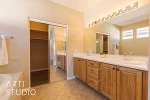 Master bathroom with vanity, a bath tub, and tile patterned flooring and door to large walk-in closet