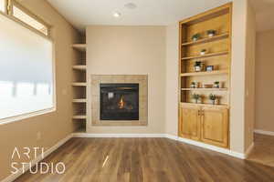 Unfurnished living room with dark lvp style flooring, a fireplace, and built in shelves