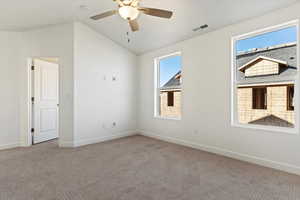 Carpeted empty room with ceiling fan and vaulted ceiling