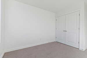 Unfurnished bedroom with light carpet and a closet