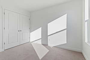 Unfurnished bedroom featuring light colored carpet and a closet