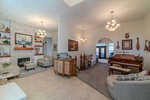 Carpeted living room with a fireplace, an inviting chandelier, and built in shelves