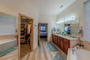 Bathroom with vanity, tiled tub, and hardwood / wood-style floors