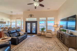 Living room with french doors, ceiling fan with notable chandelier, and light carpet