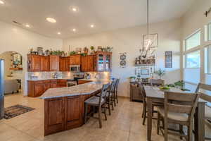 Kitchen with sink, light stone counters, appliances with stainless steel finishes, kitchen peninsula, and backsplash