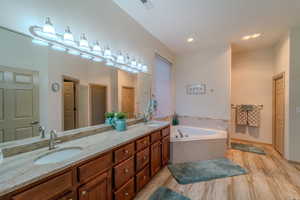 Bathroom with a washtub, vanity, and wood-type flooring