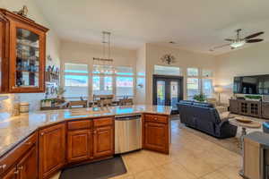 Kitchen with sink, decorative light fixtures, light tile patterned floors, dishwasher, and kitchen peninsula