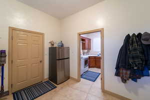 Kitchen featuring sink, light tile patterned flooring, stainless steel refrigerator, and range