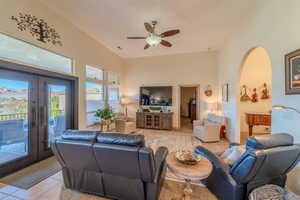 Living room with light tile patterned floors, french doors, and ceiling fan