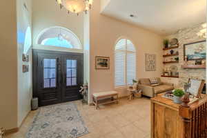 Tiled entryway featuring a notable chandelier