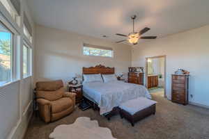 Bedroom featuring ceiling fan, light colored carpet, and ensuite bathroom