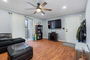 Living room with hardwood / wood-style floors, ornamental molding, and ceiling fan